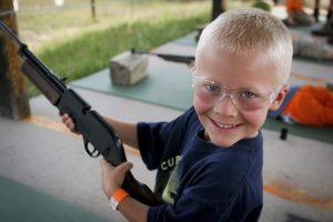 Boy happily (and safely) shoots a bb gun at camp.
